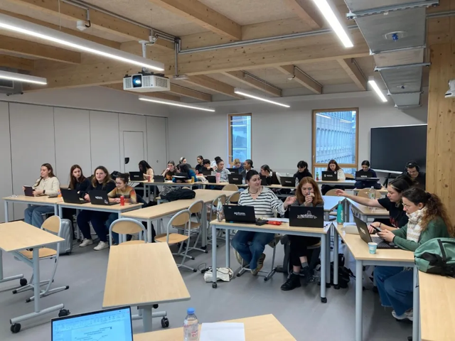 Estudantes trabalham em laptops durante aula em sala moderna